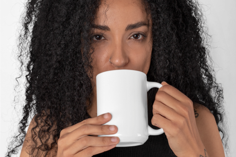 Woman drinking from a white mug against a plain background