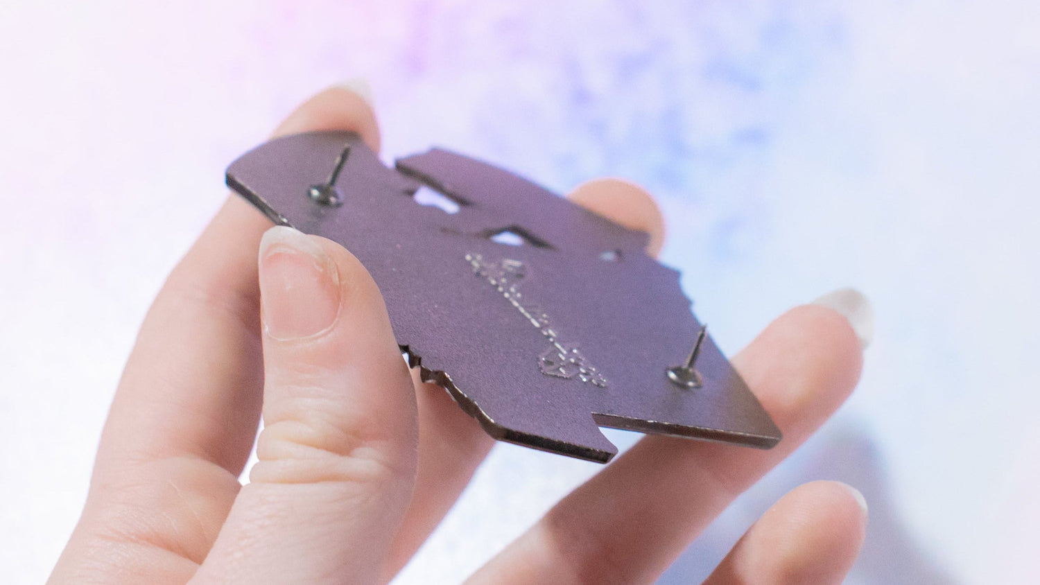 Hand holding a small purple device with a blurred colorful background